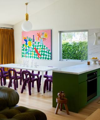 Neutral eat-in kitchen with green cabinets and purple dining chairs, plus vibrant artwork