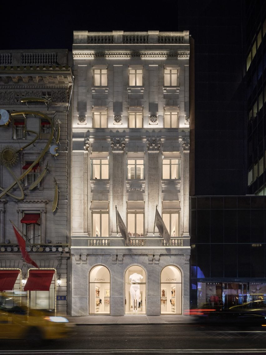 Historic Fifth Avenue building with ornate exterior details, seen at night