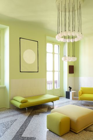 A colorful, neon yellow living room. The walls are neon yellow, as are the doors, artwork, lounge chairs and ottomans.