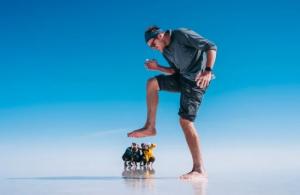 Tourist enjoys a playful perspective photo in the vast Uyuni salt flats under a clear blue sky in Bolivia.