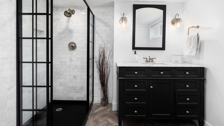 an all-white bathroom with a black vanity, mirror and shower cubicle