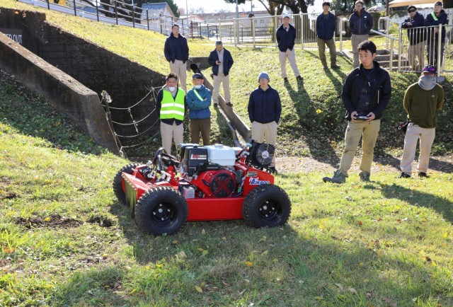 A salesman demonstrates a Sanyokiki remote-controlled lawn mower to employees of the Directorate of Public Works at Camp Zama, Japan, Dec. 6, 2024. DPW crews plan to use the mower to cut grass on the facility's steep hills.