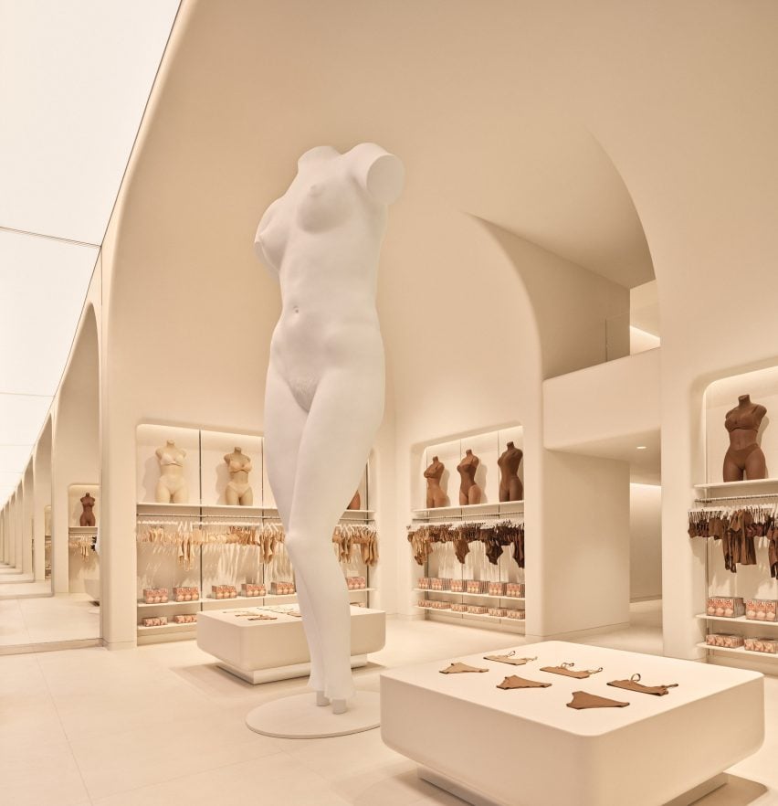 Nude colored store interior with a giant mannequin in the middle