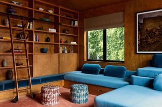 A media room with a large bright blue custom seating area and bookshelf