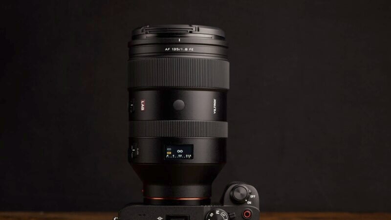 Professional camera lens mounted on a camera body against a dark background, with precise details, a focus ring and a clear brand label. The construction underlines the robust and high-quality design of the lens.