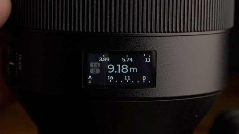 Close-up of a camera lens with a digital display showing a distance of 9.18 meters, aperture settings from 3.89 to 11, and labeled function options "Fn" and buttons "A" And "b.