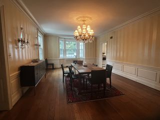 A dining room with wooden floors, wooden furniture and a chandelier above