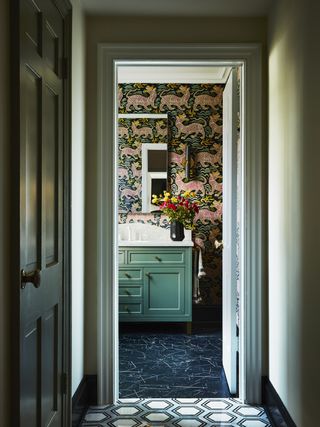 A bathroom with a green vanity and wallpaper on the walls