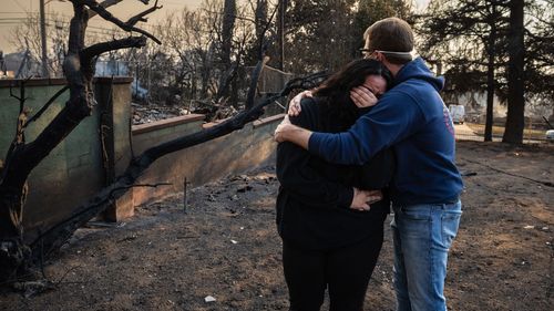 A man comforts his daughter near the charred ruins of their family home, which burned down in the Eaton Fire in Altadena, California.