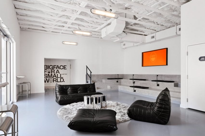 A seating area with black leather sofas and built-in concrete bleachers