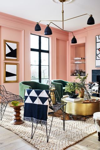 A living room with pastel pink walls and dark green armchairs