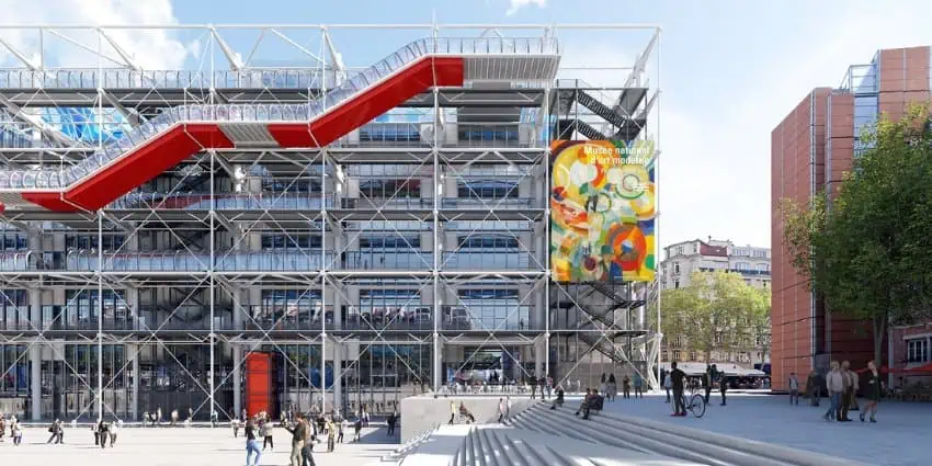 Facade of the Pompidou Center in Paris with a ruling design with terraces and a rising deck in red and white, which is available in front of the building and left a wide group of stairs and space.