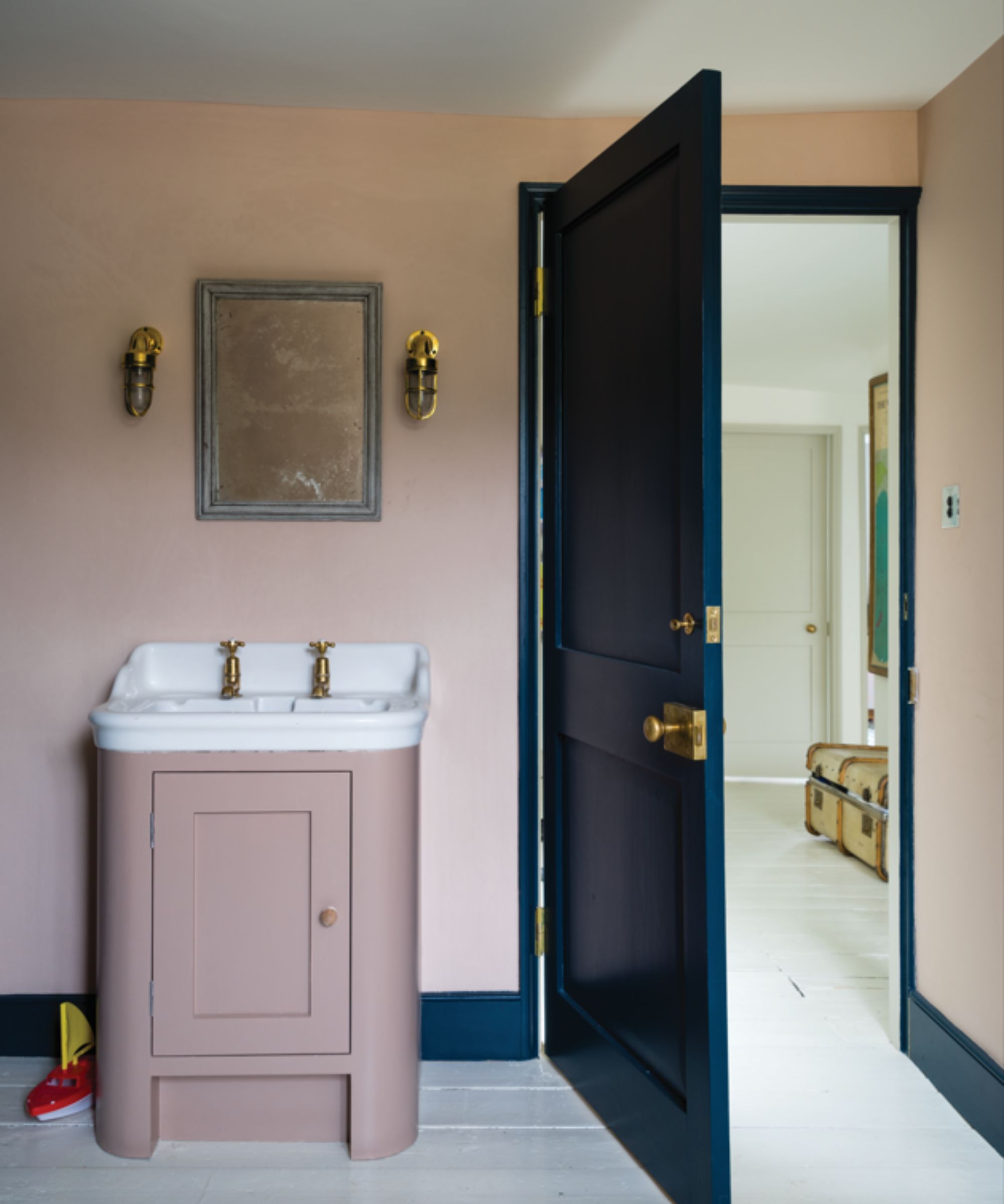 Bathroom with cleaning pink walls and vanity unit, dark blue-green door and woodwork