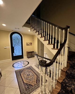 An entrance with yellow walls, a compass on the floor and stair carpet