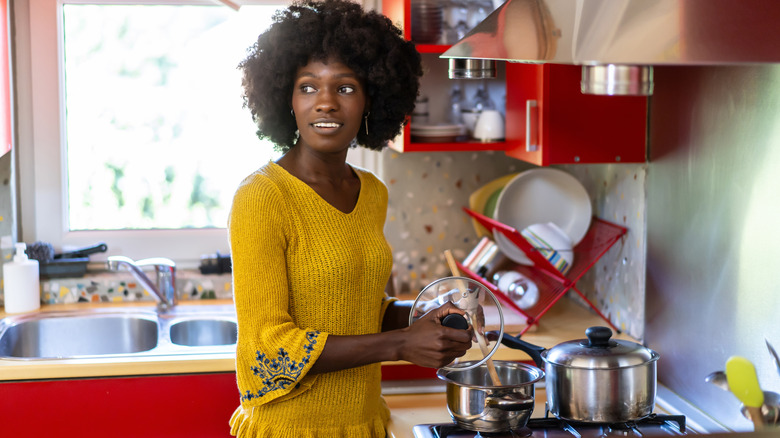 Woman who is in a kitchen with red cupboards.