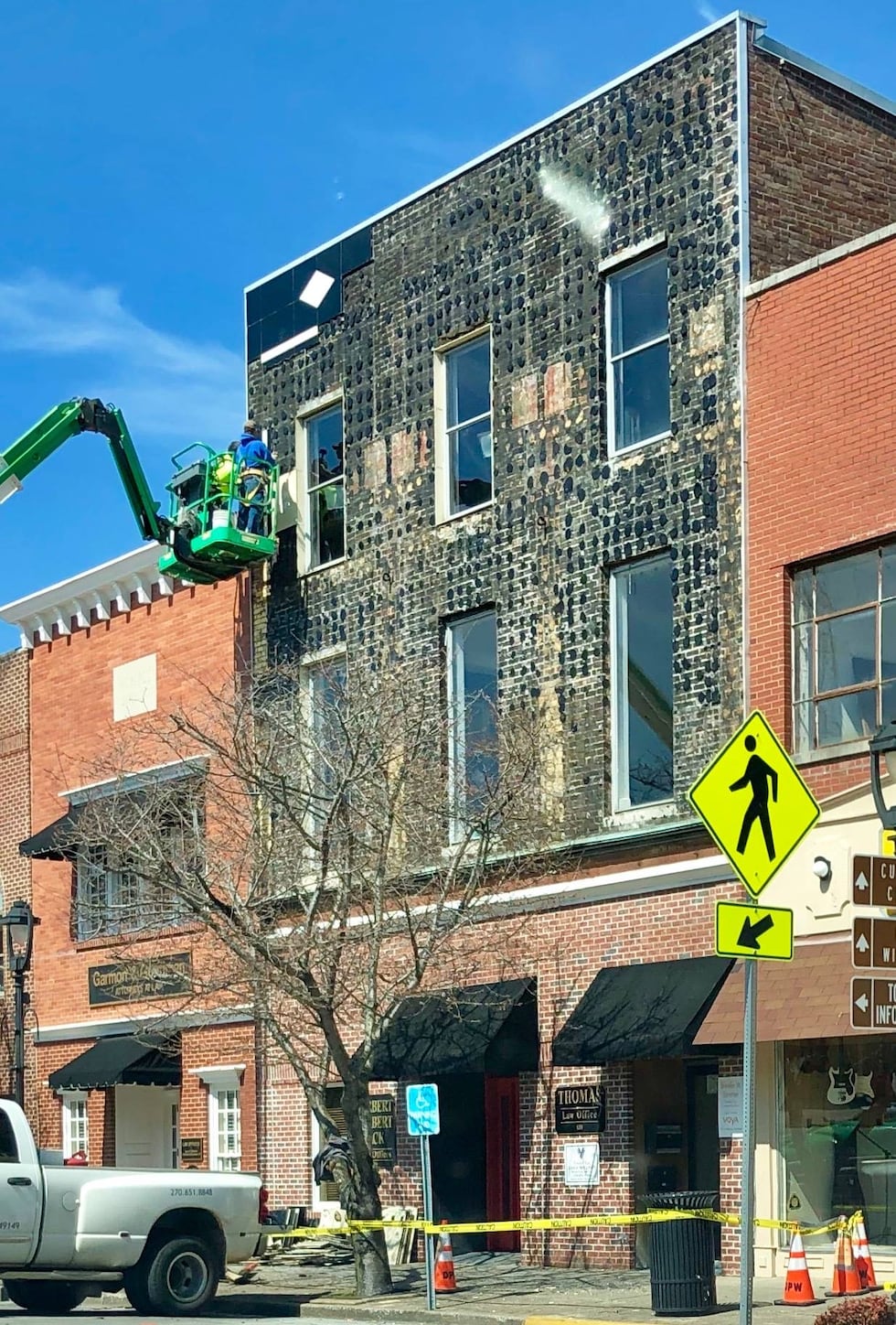 Workers remove the deteriorating vitrolite glass carefully from the facade of the Trigg theater in ...