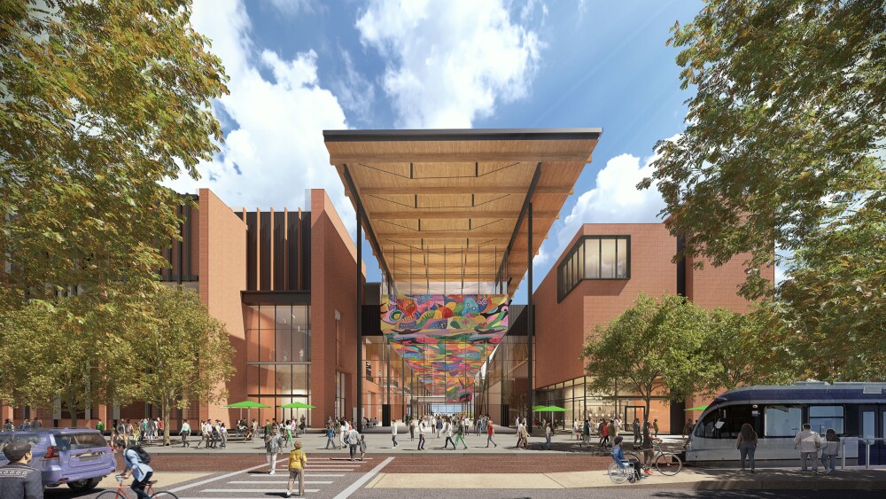 The new Austin Convention Center shows a lively urban scene with people who use, cycling and public transport. The building has a modern architecture with warm brick, large glass windows and an outstanding wooden canopy that extends over the entrance. A colorful, abstracted installation hangs under the canopy. Trees and green frame the pedestrian -friendly room, while on the right side of a rail is visible.