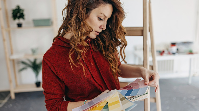 A woman in a red sweater looking for paint pallets.