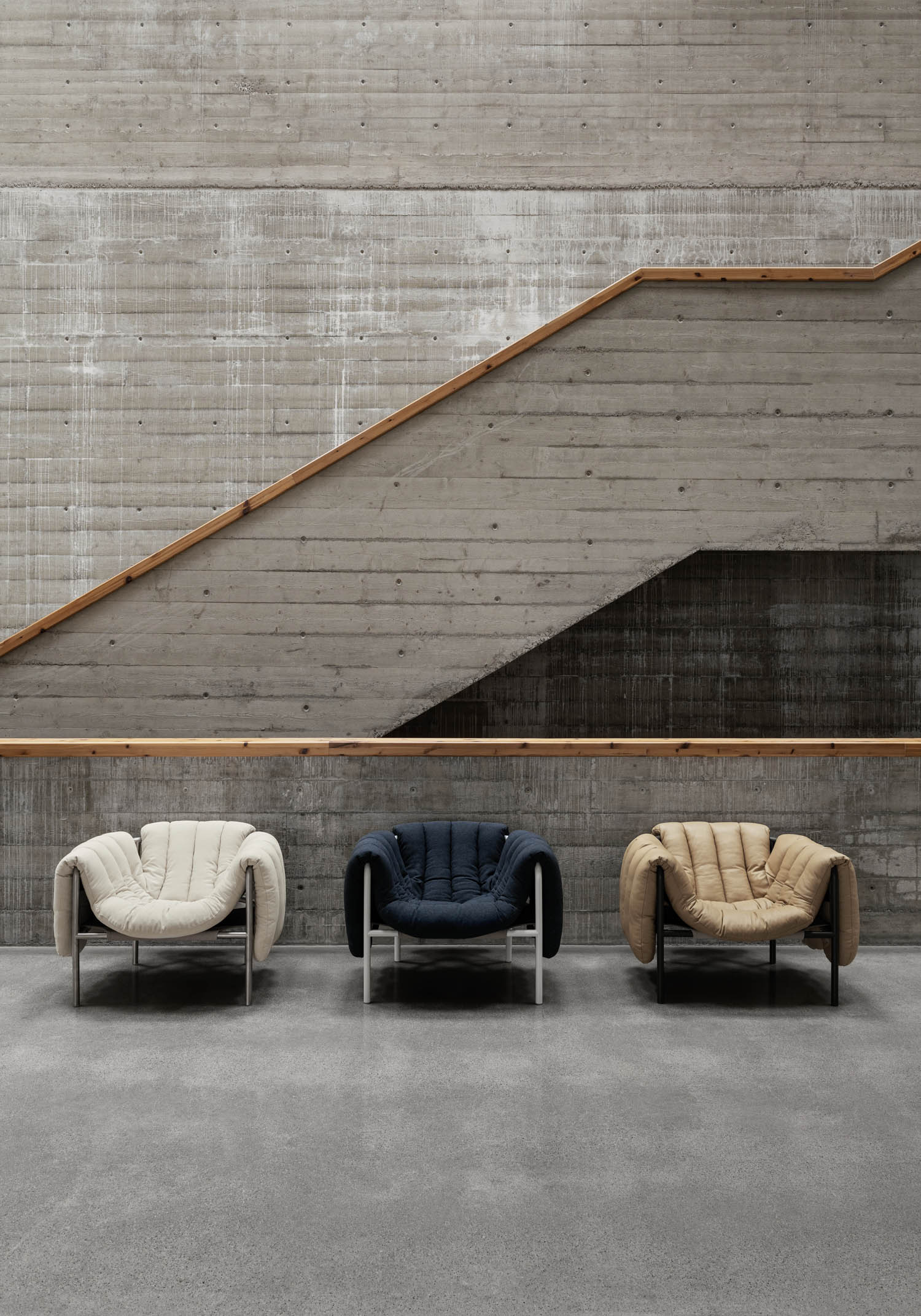 Several swollen chairs in the room with stairs in the background