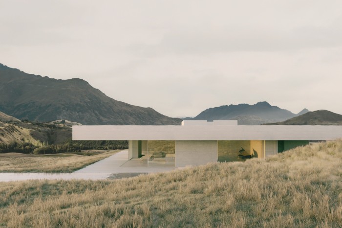 Low white concrete house with broad, happy veranda, long outdoor pool and hill behind it 