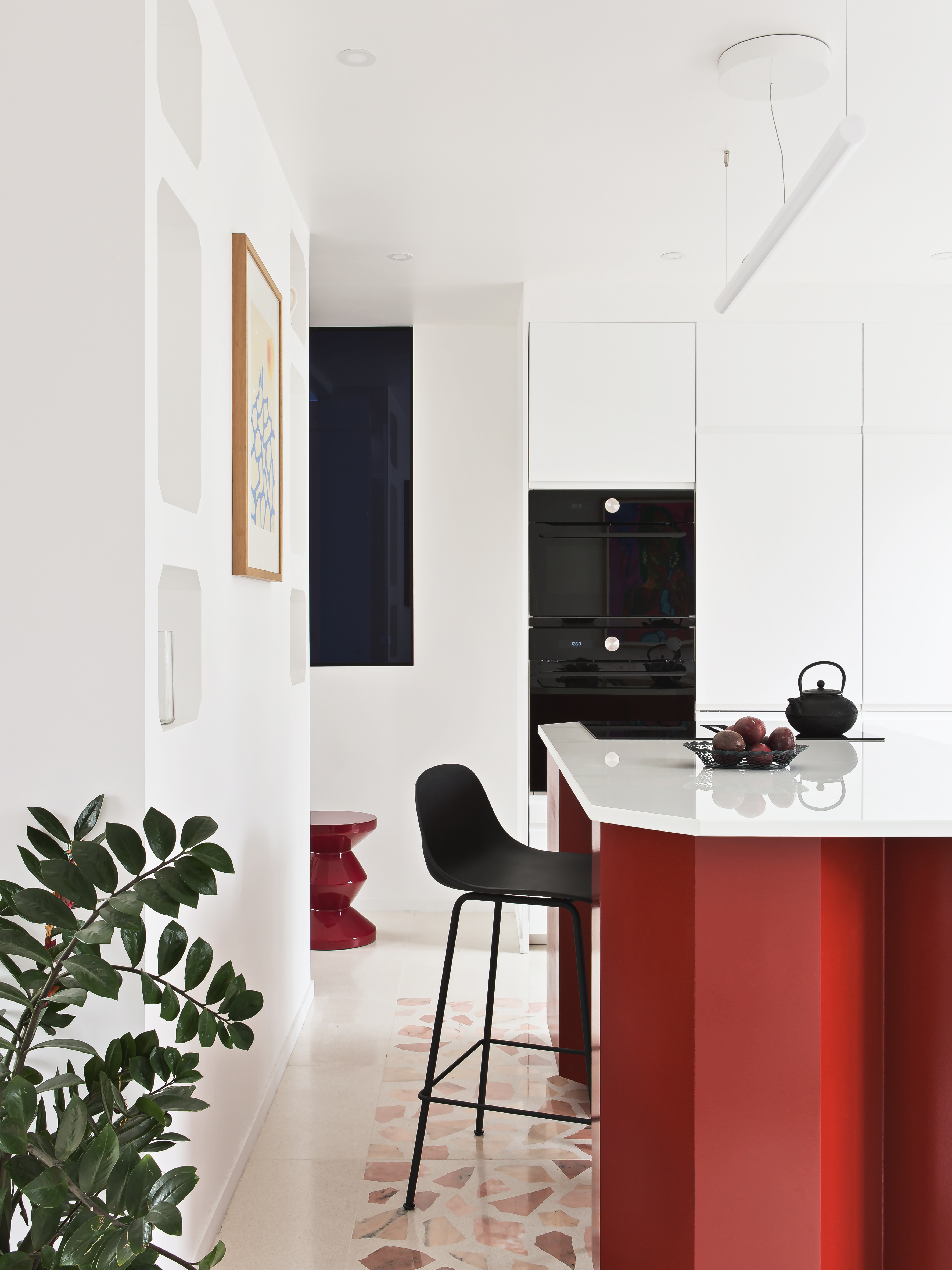 A all white kitchen with a bright red island