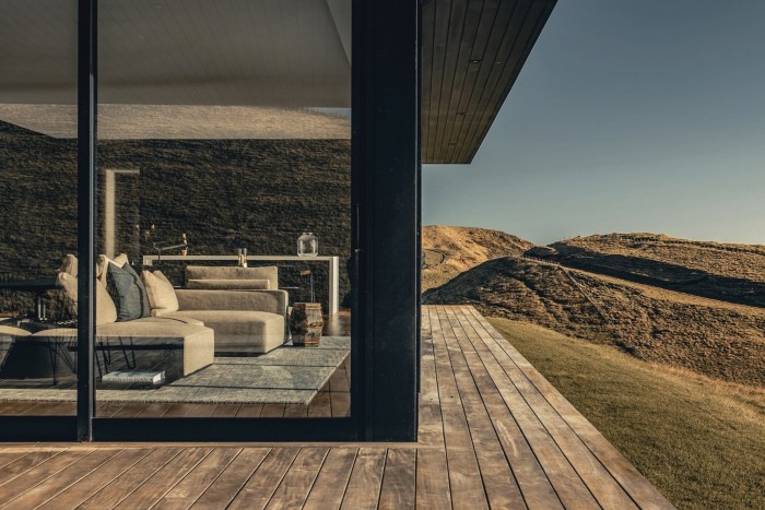 Wooden deck and space with image glass windows that show a sofa inside