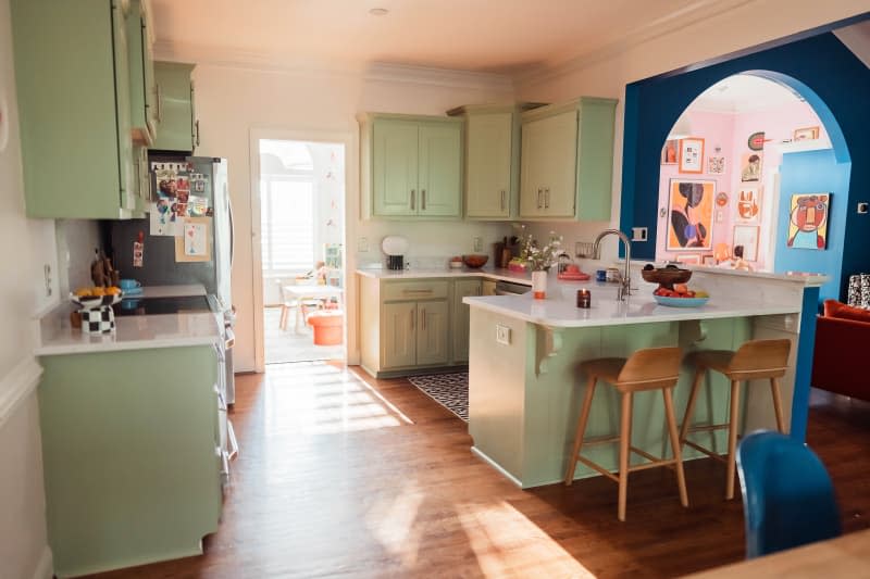 Green cupboards in white cuisine with wooden floors.
