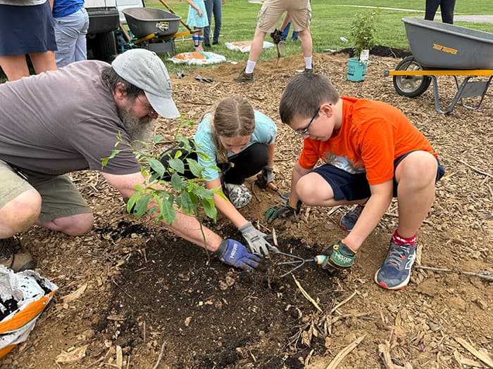 Students and an adult plant article in Swansfield's new outdoor classroom.