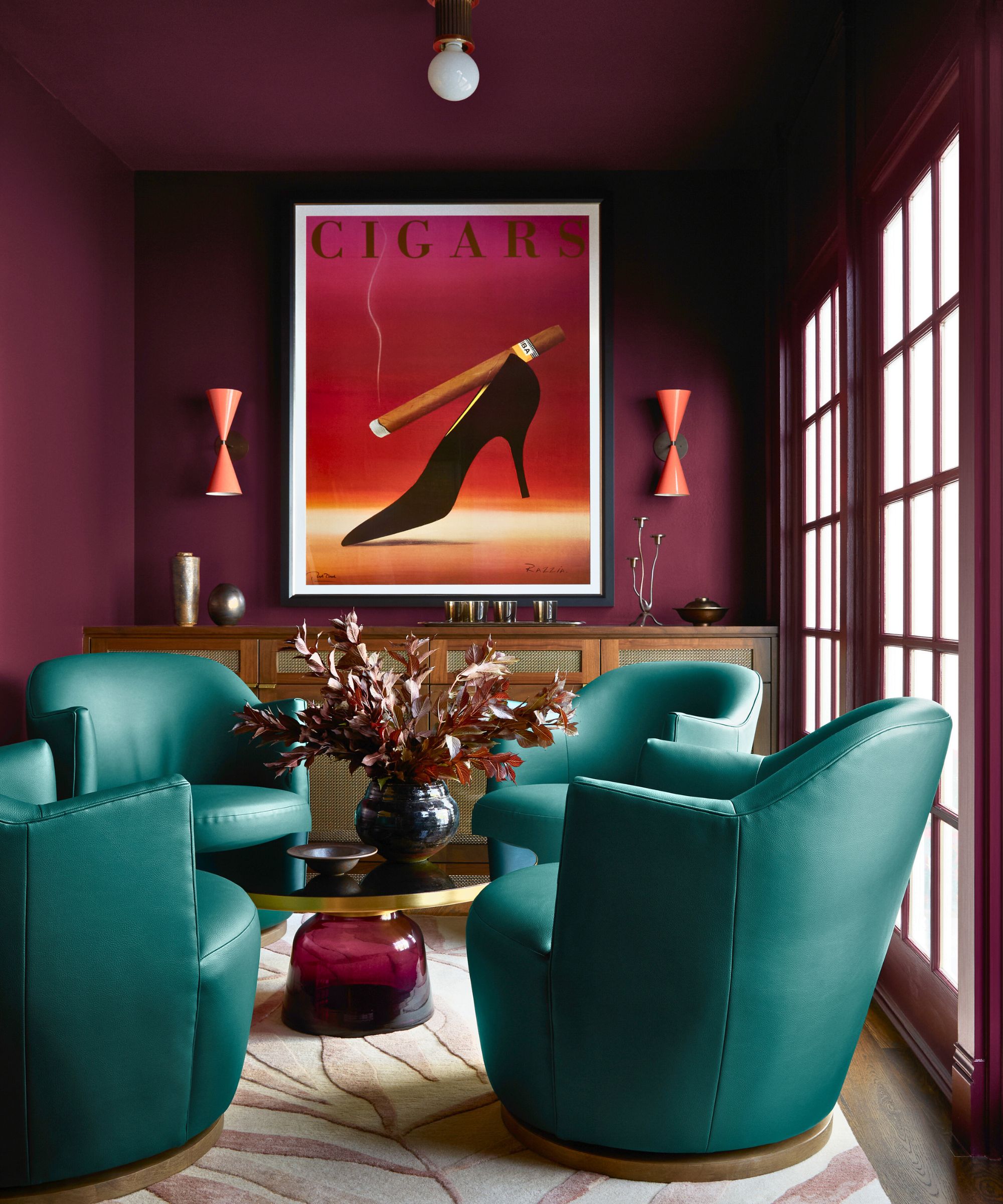 Close with dark red walls, blue -green chairs, a built wooden console and large works of art