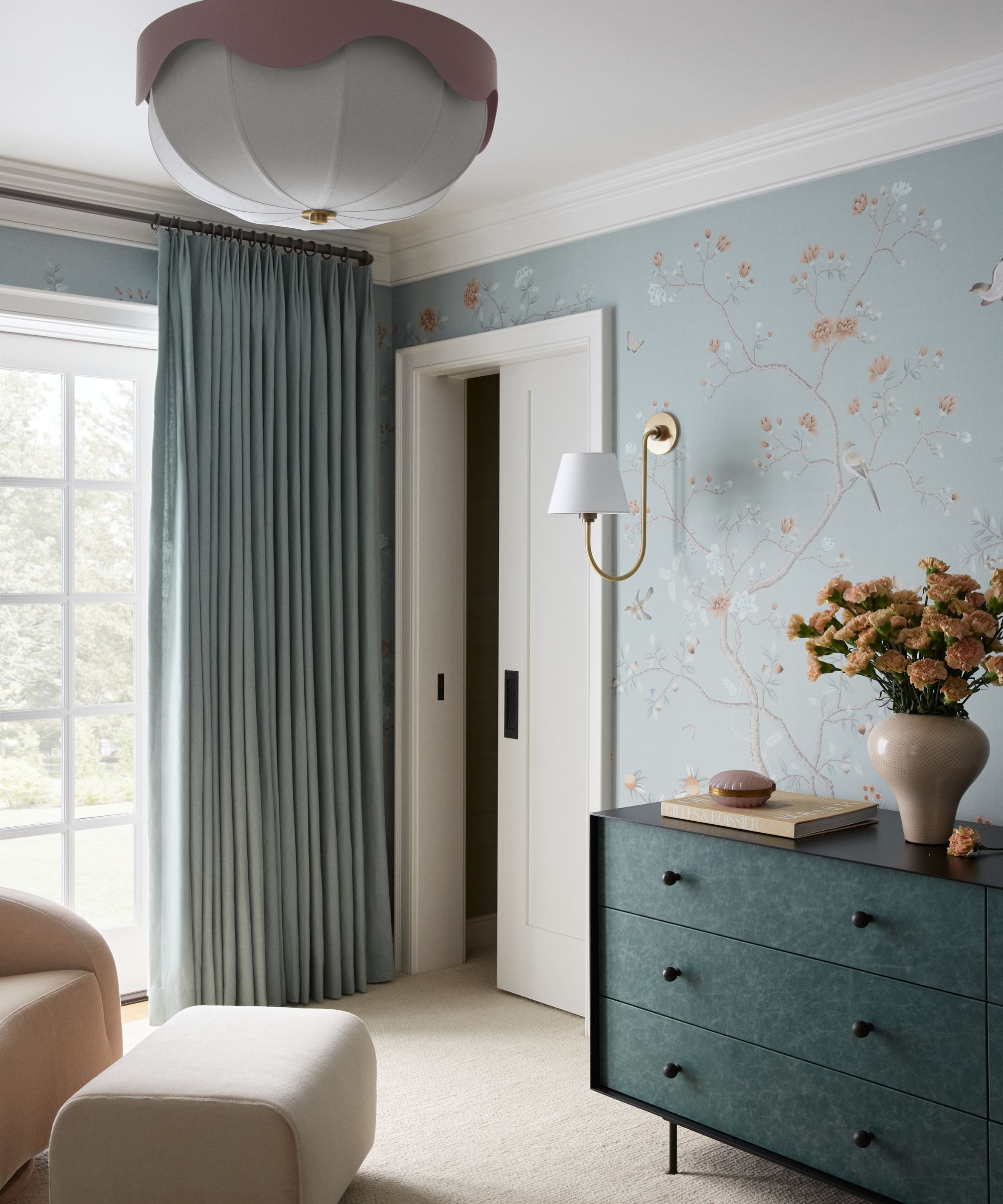 Bedroom corner with blue flowers wallpaper, blue drawers and long blue curtains