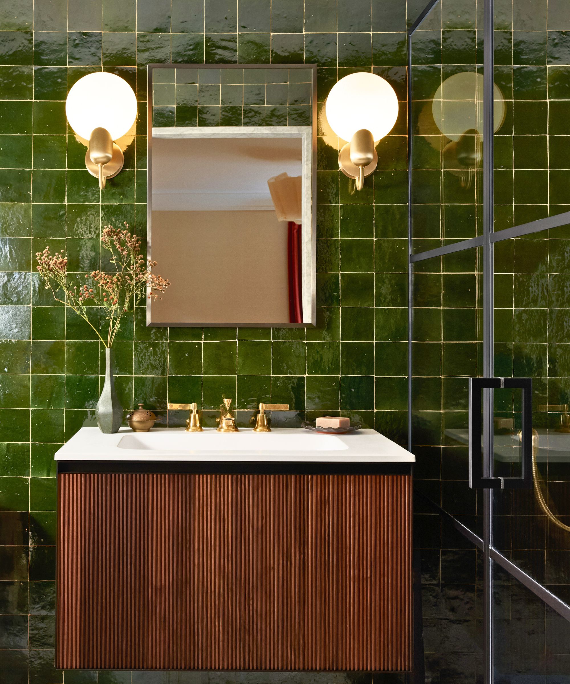 Bathroom with shiny green square tiles and a reed cabinet