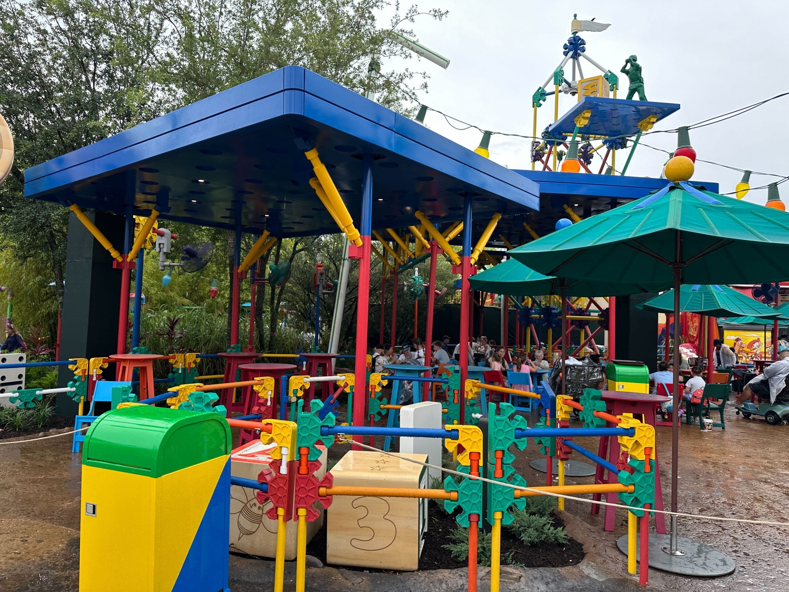 Outdoor seating area with colorful decor and tables, inspired by a playful, building block style.