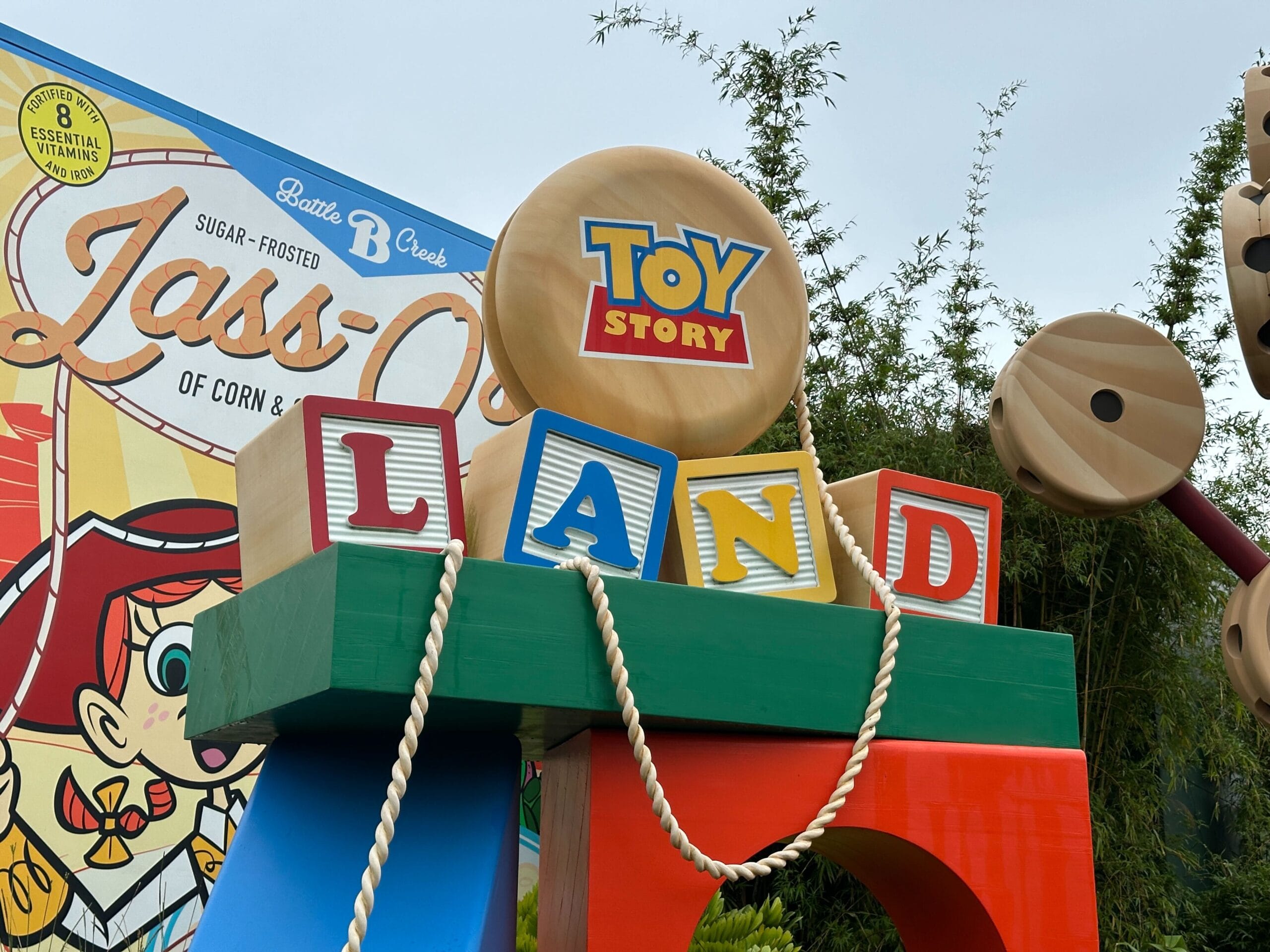 Sign with "Toy Story Land" In colorful blocks next to a vintage -müsli display in an outdoor theme park.