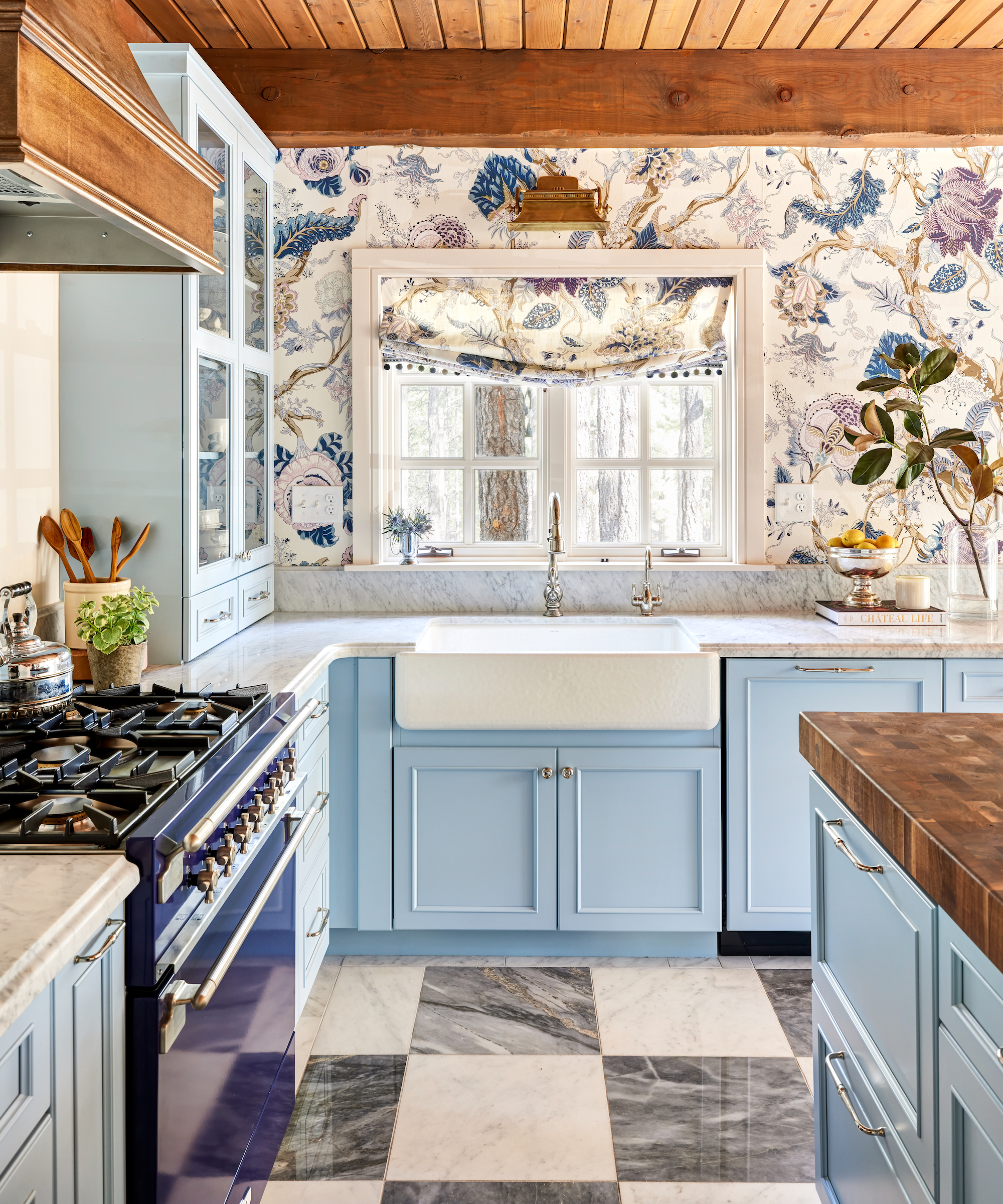 Kitchen with light blue units, range with wooden hood, butler sink, patterned