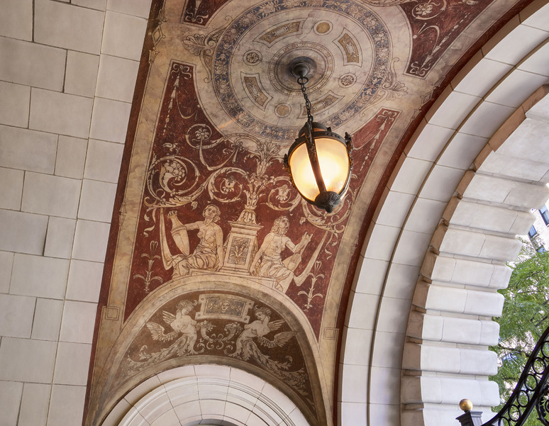 Grand Archway with a detailed work of art that represent figures with signs and a central lamp, surrounded by decorative tiles.