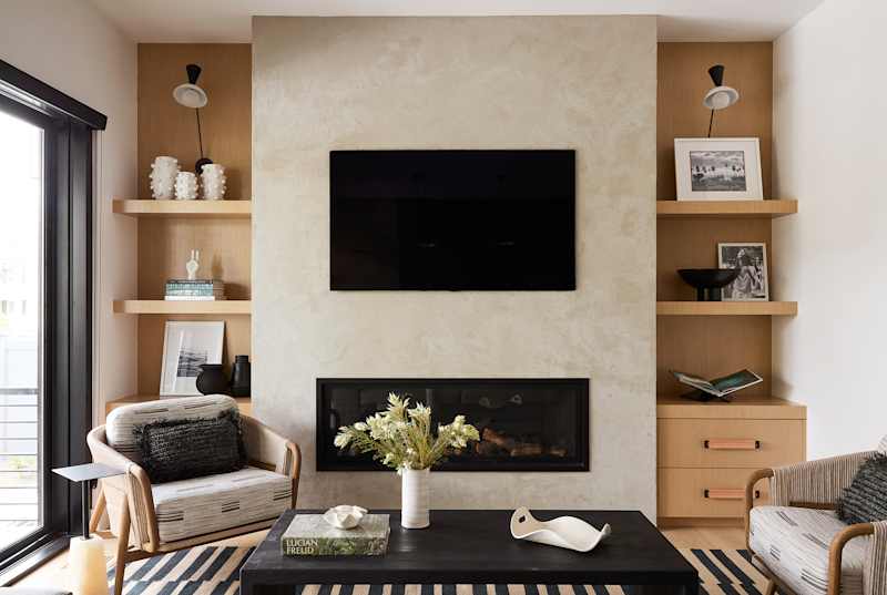Cozy living room with a modern fireplace, two armchairs, a coffee table and decorative shelves.