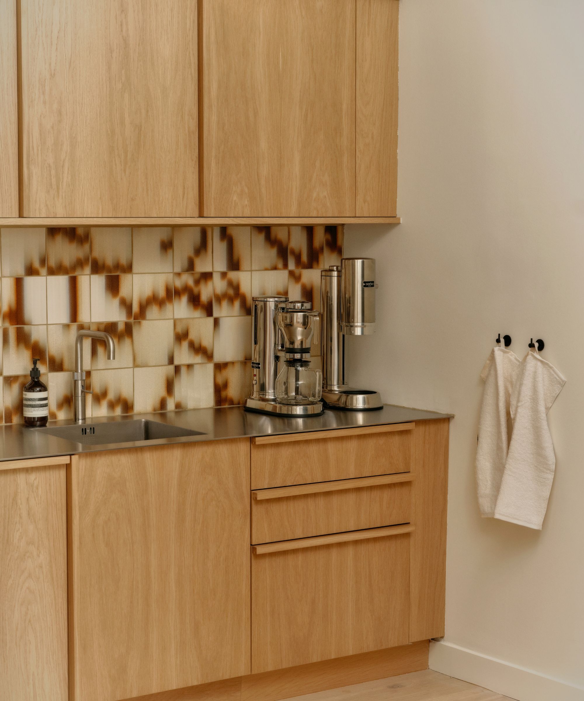 A wooden kitchen with wooden hardware and patterned tile backplash