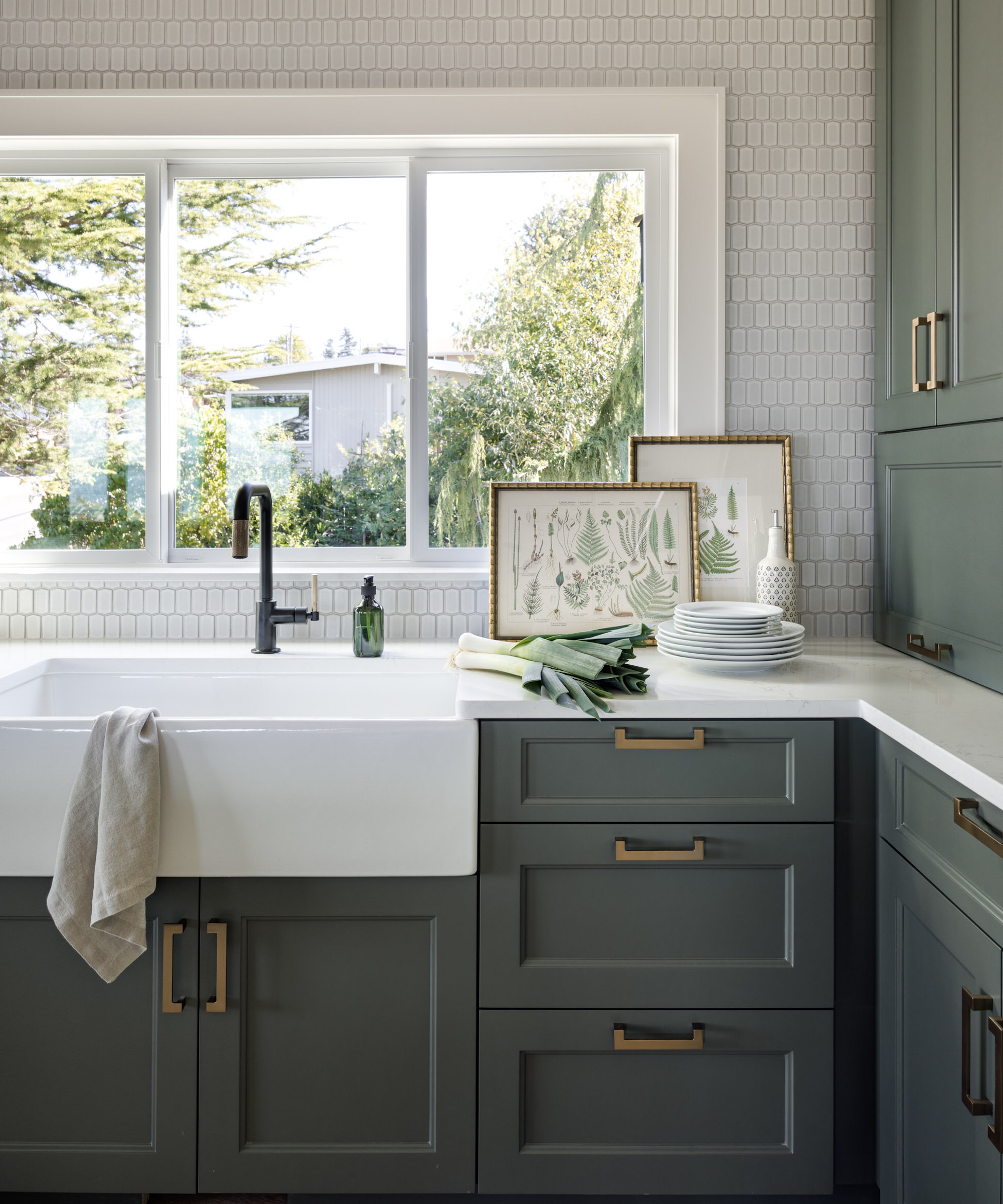 Detail of the kitchen with green cupboards, butler sink and black tap