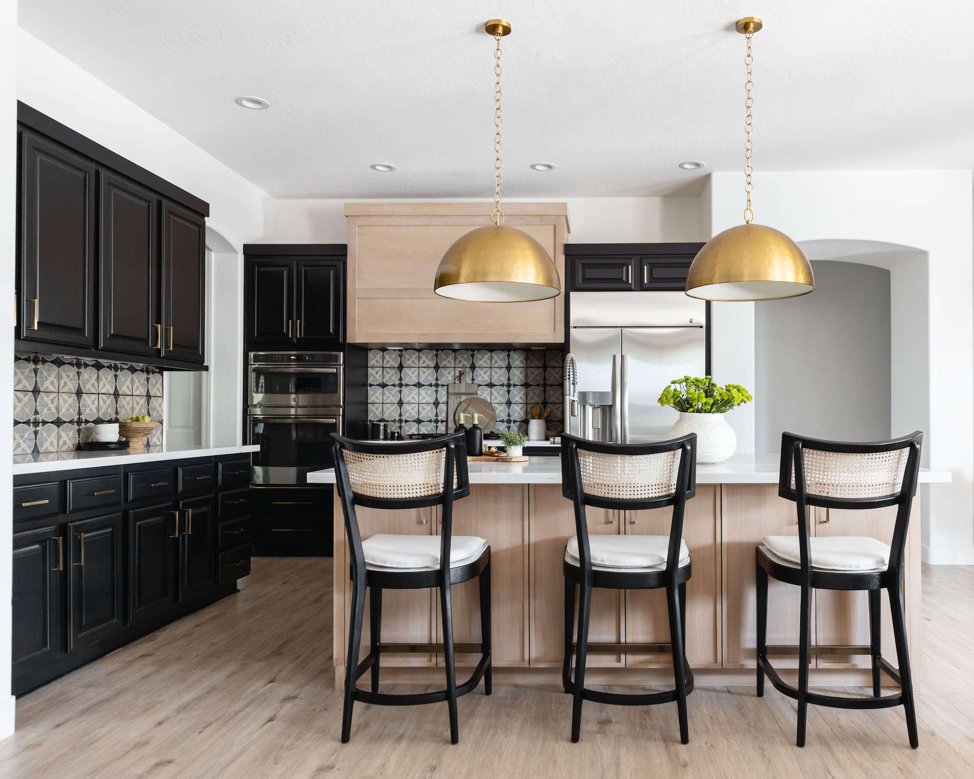 Kitchen with black cupboards and light wooden island with trailers over and bar stool