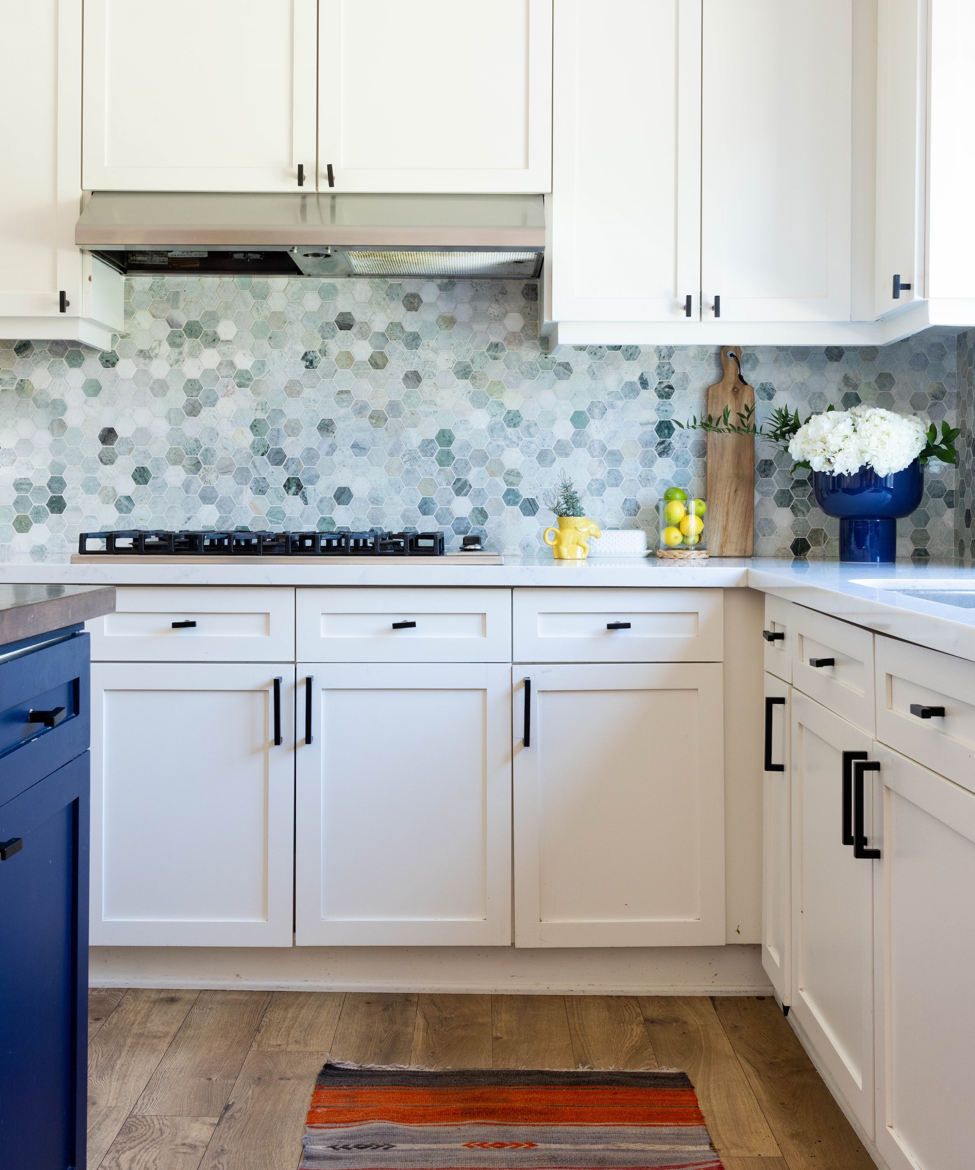 Kitchen with warm white cupboards, blue island, light worktop and blue hexagonal pattern -Backplash