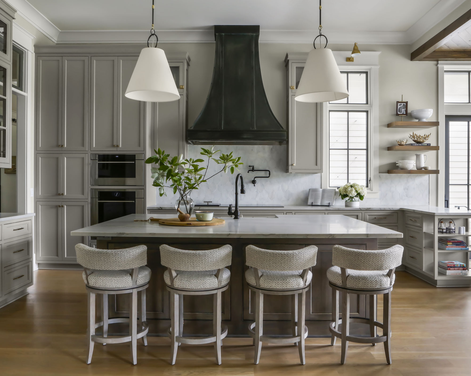 Kitchen with warm gray cupboards, island with four barhoses with trailer lights and black taps