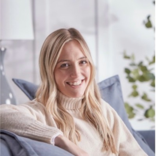 Picture of a woman in a cream -colored turtleneck sweater on a blue sofa.