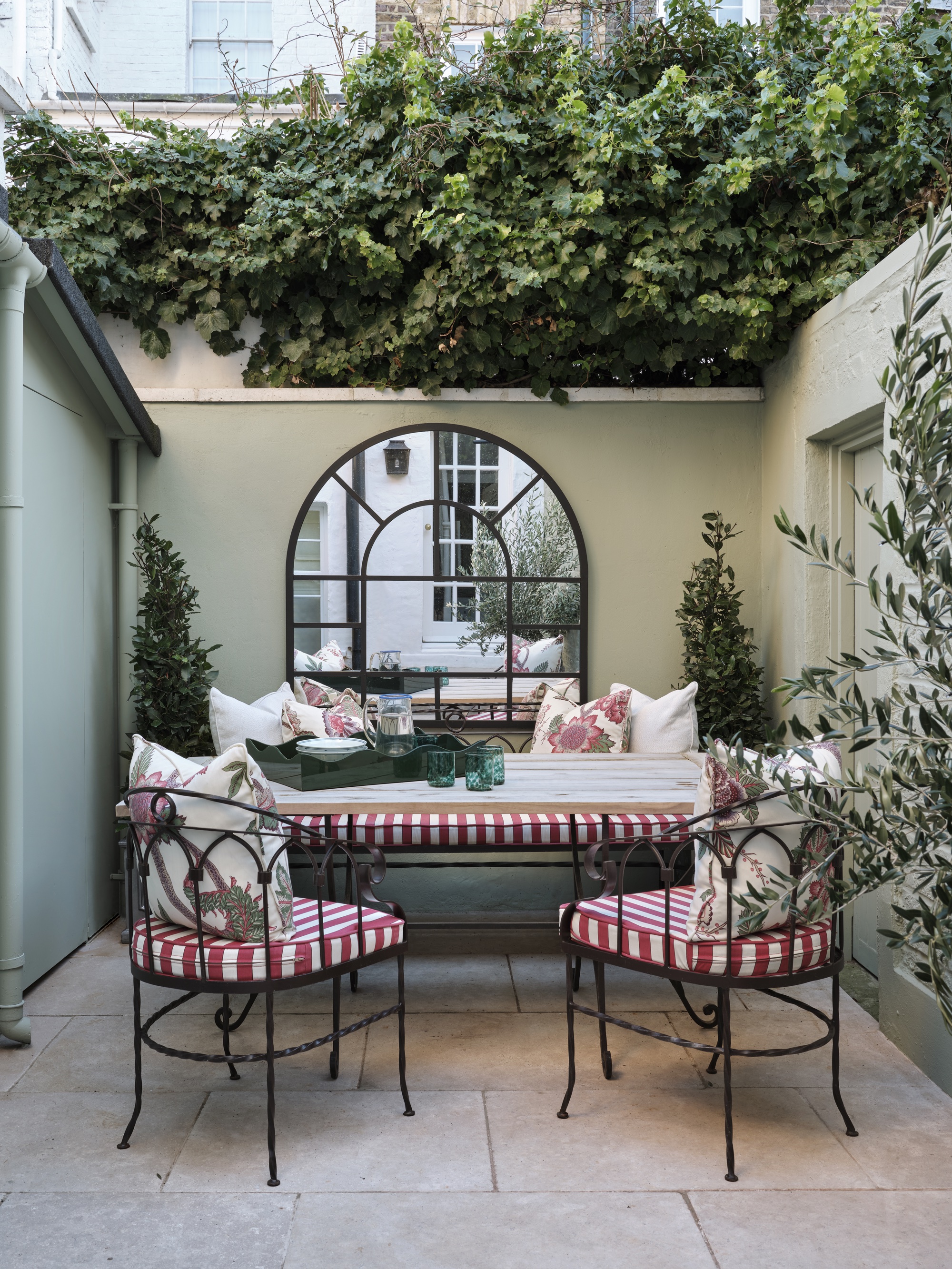 In the courtyard garden with an oversized arc window mirror and seating outdoors of Rosanna Bosom