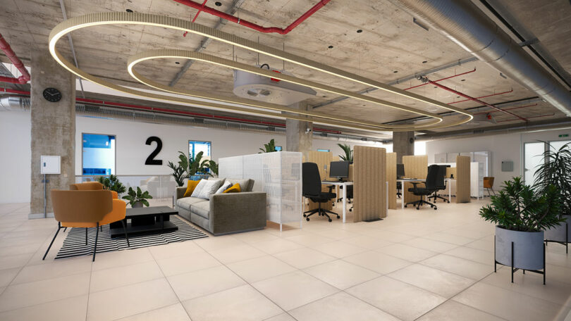 Modern open plan office with sofas, workstations, plants and concrete ceiling with exposed pipes and circular LED lighting.