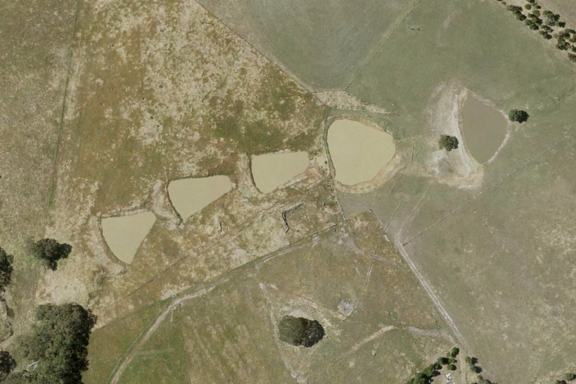 An air photo shows a number of five insenses surrounded by grass and trees.