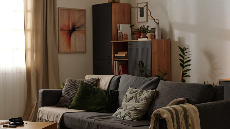 A warm grave room has orange furniture and a gray couch.