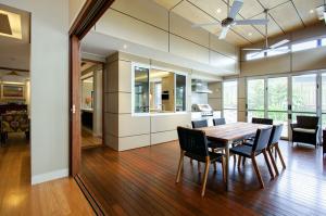 Overdacle dining room with wood and high ceilings, ceiling fans, servery and sliding doors, part of a future -proof home renovation in Indooroopilly from Dion Seminara Architecture.