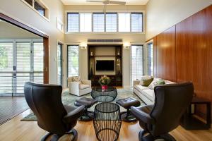 Living room with high ceilings, clerestory-louvre windows and sliding doors, which are connected by Dion Seminara Architecture with adjacent rooms in a home renovation after the war.