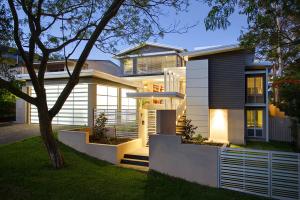 The outside view of a renovated interior after the war at dusk at dusk, which shows modern architectural updates with layered roof lines, large windows and soft landscape lighting.