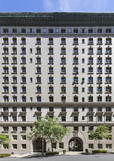 High white historical building with many windows, green roof cladding and curved inputs that compete against a clear blue sky.